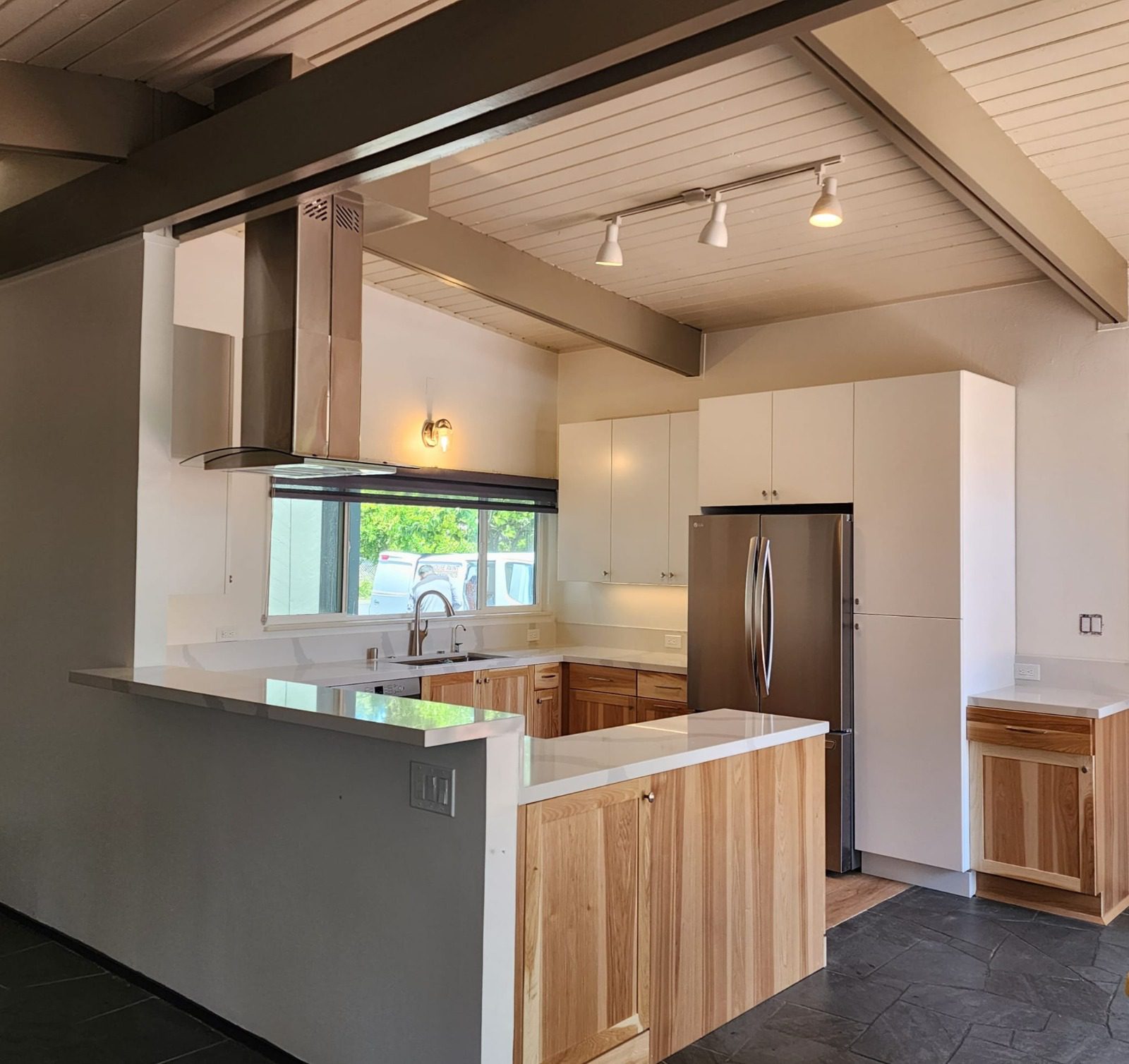 Modern kitchen with white and wooden cabinets, stainless steel appliances, a large island, and overhead lighting.